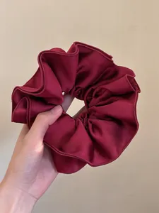 Detailed close-up of dark red satin scrunchie with rich pleats and silk texture