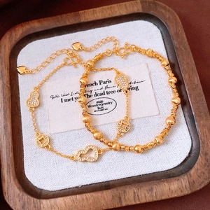 Détail de pendentifs gourde plaqués or 24 carats sur d'élégants bracelets superposés