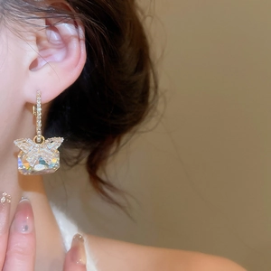 Macro shot of a butterfly earring with a large rectangular zircon on a model's ear