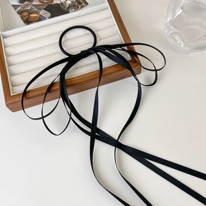 Detail of elegant black satin bow hair tie with long ribbons on a velvet jewelry tray