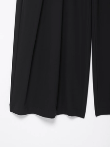 Close-up of black wide-leg trousers showing neat hem stitching and draped fabric texture