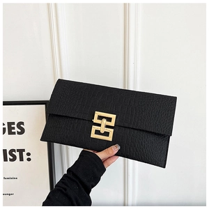 Vue détaillée de la texture crocodile noire et du fermoir doré de la pochette enveloppe