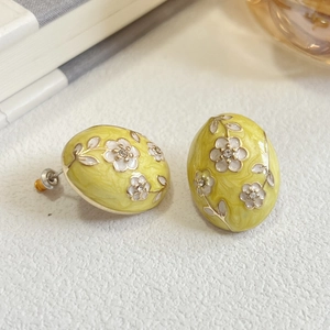 Close-up of vintage oval yellow enamel earrings with white flower detail and crystals