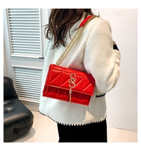 Detail of red quilted PU leather shoulder bag with gold logo and tassel accent
