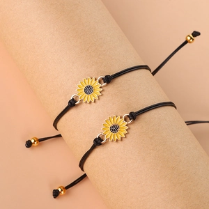Detail view of woven black cord bracelets with yellow enamel sunflower charms and gold beads