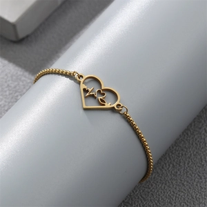 Close-up of golden heartbeat heart charm on a delicate stainless steel chain bracelet