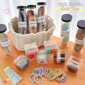 Close-up of high elasticity hair ties in a transparent box on a wooden desk