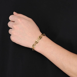 Detail of coffee bean link bracelet in gold plating worn on wrist with black background