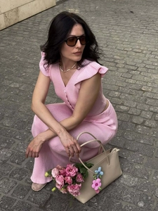 Detail of pink knitted V-neck top with ruffle sleeves and matching pants on model