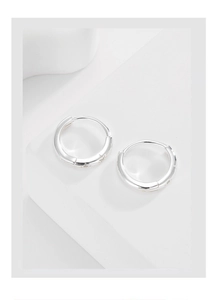 Minimalist silver sterling star circle earrings set on a white geometric platform