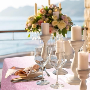 Detail of pink sequin tablecloth on a wedding table with sea view and floral decor