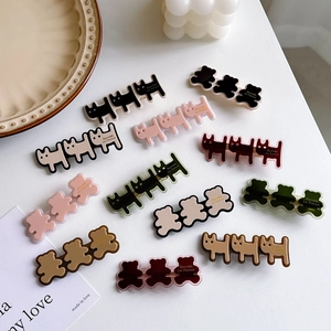 Colorful resin bear and cat hair clips set on a minimalist white tabletop background