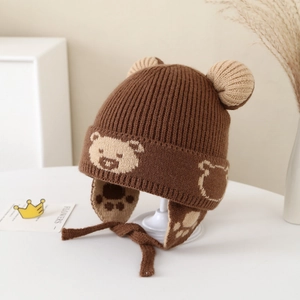 Detailed close-up of brown knit bear hat with ear flaps and soft braided chin straps