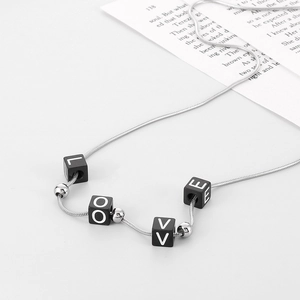 Minimalist silver steel necklace with black cube beads spelling LOVE on white background