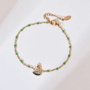 Detailed view of sailboat charm on stainless steel bracelet with green enamel beads