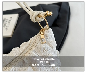 Detail of white pleated shoulder bag featuring gold hardware and magnetic snap closure