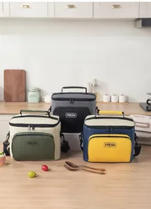 Macro shot of three insulated lunch bags in grey, green, and blue on a wooden table