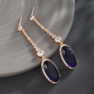 Detail of luxury rose gold earrings featuring deep blue oval gems and pavé zircon stones