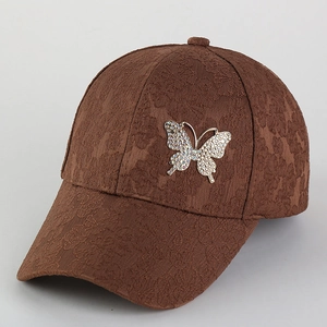 Detail of floral embossed fabric on brown baseball cap with rhinestone butterfly buckle