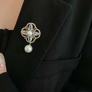 Detail of gold flower brooch with pearls and crystals on a professional black blazer