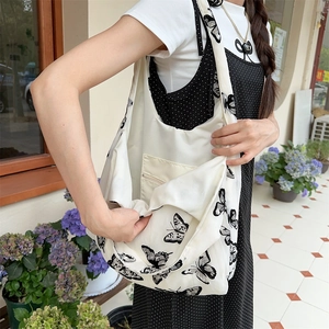 Detail of the white canvas tote with butterfly print showing the zippered inner pocket