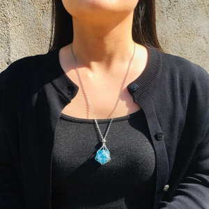 Detail of blue crystal dice pendant with silver geometric metal wire mesh wrap