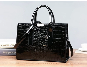 Close-up of black crocodile pattern patent leather handbag with silver hardware details
