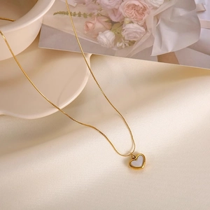 Elegant gold titanium heart necklace with white shell inlay on silk fabric