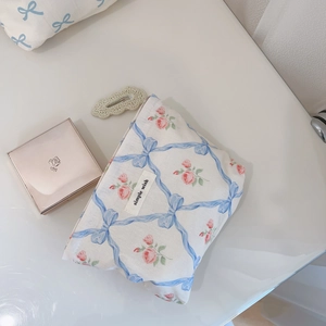 Détail d'une trousse à maquillage florale avec rubans bleus et roses sur table