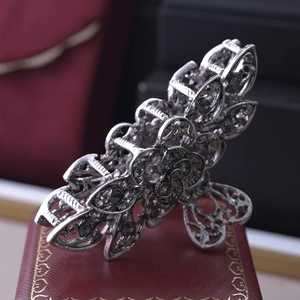 Close-up of silver flower hair claw clip with dark rhinestones on a jewelry box