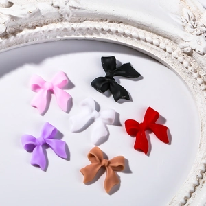 3D matte resin bow nail charms in six colors displayed on a decorative white tray