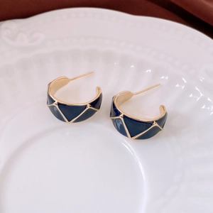 Detail of 18k gold plated C-shape earrings with dark blue geometric enamel texture