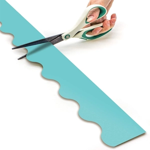 Cyan blue scalloped border trim sticker for classroom bulletin board being cut by scissors