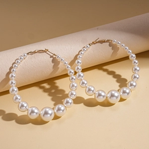 Detailed close-up of gradient faux pearls on gold circular earrings with metallic clasp