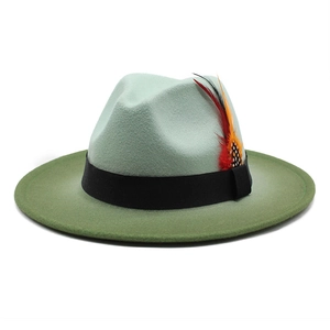 Detail of gradient green wool fedora with black ribbon and a colorful feather accent