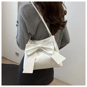 Vue détaillée d'un sac à bandoulière blanc avec un grand nœud décoratif sur un mannequin
