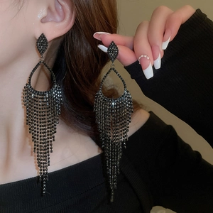 Macro shot of long black tassel earrings with sparkling rhinestones and drop-shaped stud