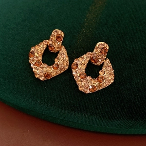 Gros plan de boucles d'oreilles dorées vintage avec cristaux champagne sur velours