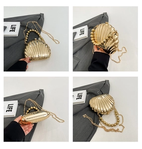 Detail view of golden shell evening bag with pearl bead handle and metal chain strap