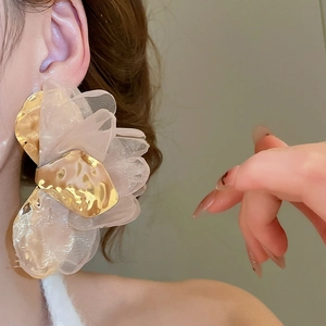 Close-up of pink chiffon flower earring with hammered gold metal texture on model