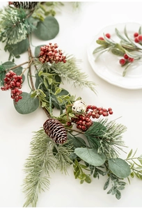 Detail of Christmas garland with pine needles, red berries, pine cones and gold bells