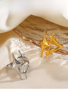 Detailed close-up of gold and silver starburst open rings on elegant silk and amber glass