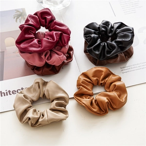 Detailed flat lay of six PU leather scrunchies in burgundy, pink, brown, and beige colors
