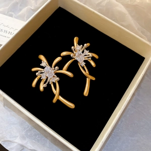 Close-up of golden firework stud earrings with zircon inlay in a premium jewelry box
