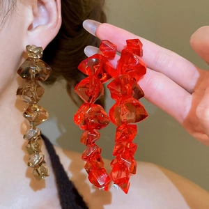 Macro shot of oversized irregular crystal acrylic earrings in red and amber brown