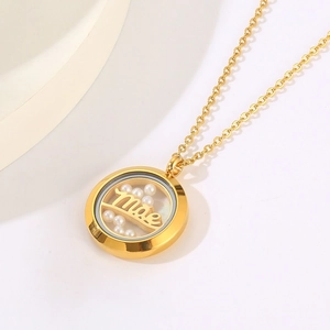 Macro shot of gold necklace with round pendant featuring white pearls and Mae lettering