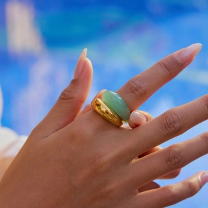 Primo piano dell'anello dorato spesso e dell'anello in pietra verde indossati