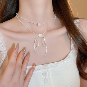 Close-up of double layer pearl choker with heart pendant and bead bow on collarbone