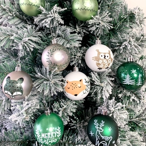 Detail of Christmas tree ornaments with fox and owl motifs on a snow-covered tree