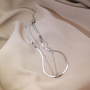 Detail of silver double-layered snake chain necklace with minimalist cube pendant